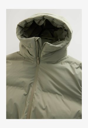 Ljust grön puffjacka med hög krage och huva. Har en central dragkedja och slät, quiltad yta. Minimalistisk design.