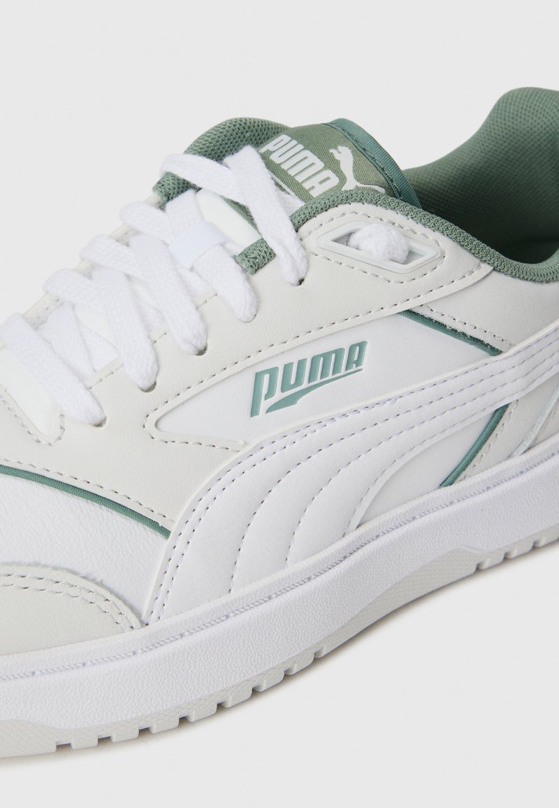 Sneaker bianca in pelle con accenti verdi e tessuto testurizzato sulla linguetta. Presenta lacci bianchi, una suola in gomma e un marchio Puma prominente.