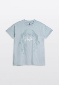 Jasnoniebieska koszulka z krótkim rękawem z delikatnym graficznym nadrukiem czaszki i białym tekstem umieszczonym na środku klatki piersiowej.