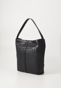 Sac à main tissé noir avec une forme structurée, présentant une sangle plate et large ainsi qu'une texture lisse. Remarquable pour son motif de tissage complexe.