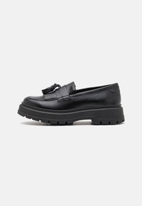 Mustad musta nahast loafers, millel on jäme kummist tallaga, kaunistatud tassi aktsendiga ja stiilse disainiga. Sile tekstuur ja ümmargune varvas.