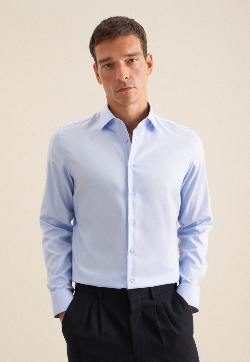 Lichtblauwe button-up shirt met een puntige kraag en lange mouwen. Heeft subtiele stikseldetails en een gladde, licht gestructureerde stof.