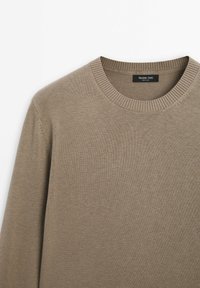 Beige Strickpullover mit rundem Ausschnitt und gerippten Bündchen. Hergestellt aus einem weichen, strukturierten Stoff, mit einem Etikett von Massimo Dutti.