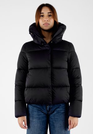 Giacca a vento nera con colletto alto, caratterizzata da sezioni trapuntate, una cerniera frontale e bottoni a pressione dorati. Abbinata a jeans in denim blu.