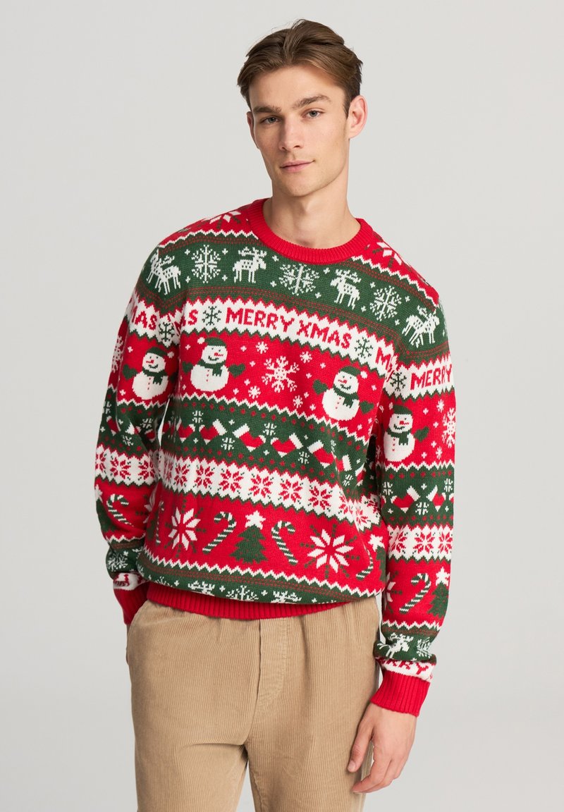 Pullover natalizio in maglia con motivi rossi, verdi e bianchi, tra cui pupazzi di neve, renne e fiocchi di neve. Collo e polsini a coste.