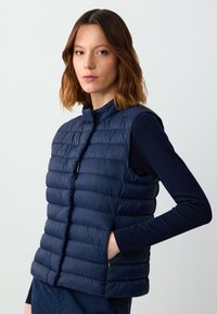 Marineblauer Puffer-Weste mit horizontaler Steppung, hohem Kragen und Frontreißverschluss. Verfügt über Seitentaschen und eine glatte, leichte Textur.