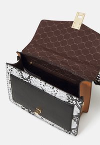 Sac à main en imprimé serpent noir et blanc avec un fermoir doré, doté d'une doublure intérieure marron avec un motif ALDO et de compartiments spacieux.
