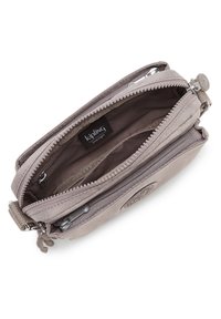 Portafoglio Kipling in tessuto grigio chiaro con chiusura a zip, tasche interne e toppa con logo. Presenta una texture liscia e dettagli della cerniera in contrasto.