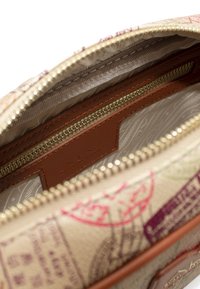 Borsetta beige con zip aperta, decorata con francobolli stampati colorati, che mostra l'interno in tessuto beige a fantasia e una tasca interna con zip rifinita in marrone.