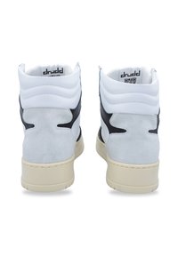 Zapatillas altas con una parte superior de cuero blanco, acentos de ante gris, detalles en negro y una suela de goma beige con acabado texturizado.