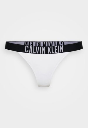 Balti tanga apakšveļa ar teksturētu audumu un melnu elastīgu jostu, kas rotāta ar kontrastējošo pelēko "Calvin Klein" logo.