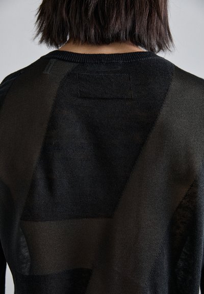 Schwarzer Strickpullover mit einer Mischung aus transparenten und undurchsichtigen Texturen, geometrischen Einsätzen und einem klassischen Rundhalsausschnitt.