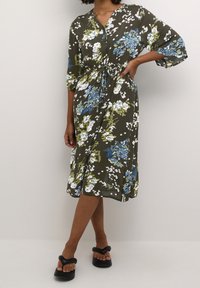 Florales Midikleid in Olivgrün. Mit blauen und weißen Blumen, tailliert, V-Ausschnitt und lockeren Ärmeln. Hergestellt aus leichtem Stoff.