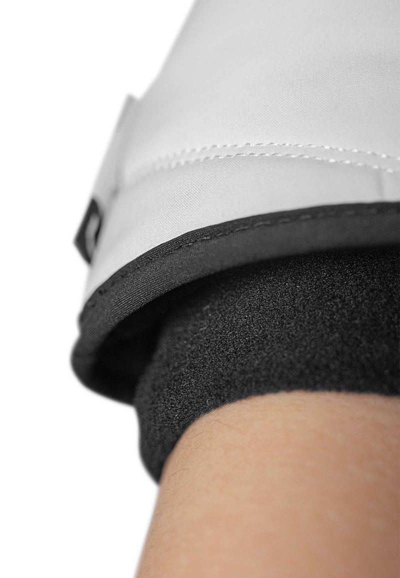 Grauer Stoffhandschuhbund mit schwarzem Rand; glatte Textur oben, die in ein weiches, strukturiertes schwarzes Material am Handgelenk übergeht.