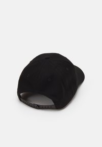 Melnā beisbola cepure ar izliektu malumu, auduma materiālu un regulējamām siksniņām aizmugurē ar vairākiem caurumiem.