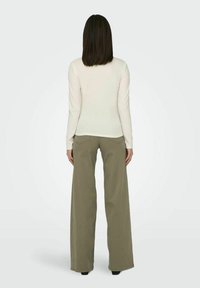 Lange mouw crème top gecombineerd met losvallende, olijfgroene wijde broek. Glad stof met een eenvoudig ontwerp, geen zichtbare patronen of versieringen.