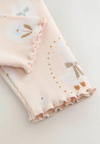 Rosa gerippter Stoff mit einem gewellten Rand, dekoriert mit fantasievollen Tiermustern und goldenen Punkten, die ein verspieltes Design schaffen.