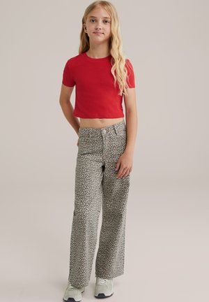 T-shirt rouge courte à manches courtes associée à un pantalon large à imprimé léopard gris clair et des baskets grises. Design simple et coupe décontractée.