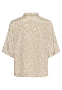 Blouse beige à manches courtes avec des motifs abstraits blancs, un col montant et une coupe ample. Tissu texturé avec une finition lisse.