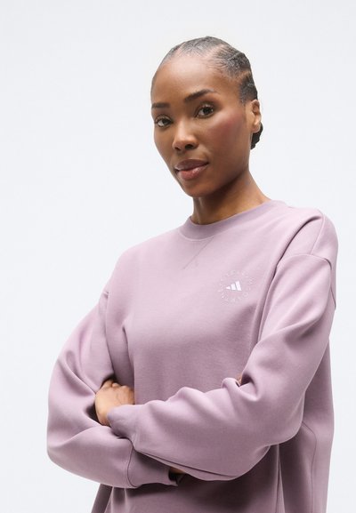 Ανοιχτό μωβ φούτερ με στρογγυλή λαιμόκοψη, ριγέ ώμους και κεντημένο λογότυπο στο στήθος. Απαλό, υφασμάτινο ύφασμα με υφή, άνετη εφαρμογή.