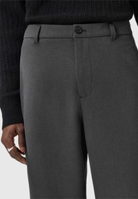 Dark gray tailored trousers with a smooth texture, featuring a button closure, slanted side pockets, and a flat front design.