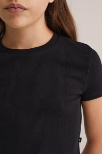 Černé žebrované tričko s krátkými rukávy a kulatým výstřihem, vyrobené z texturované látky a s malou logovou značkou na bočním švu.