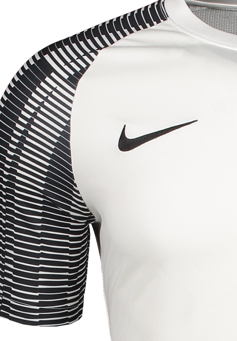 Nike Sportshirt in Weiß mit strukturierten, schwarzen Streifen an den halben Ärmeln. Verfügt über ein schwarzes Nike-Logo auf der oberen Brust. Glatte Stoffoberfläche.