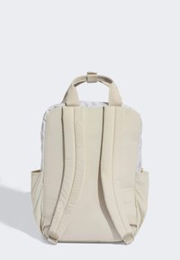 Zaino beige con spallacci imbottiti, manico superiore, tessuto strutturato e tasche laterali per riporre oggetti, caratterizzato da un design minimalista.