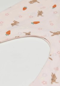 Světlé růžové plátno s motivem hnědých králíčků, oranžových mrkví a malých květin. Má zapínání na druky poblíž výstřihu.