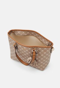 Beige totebag met een patroon op de buitenkant, bruine leren handvatten en een binnenzak met rits. Heeft gedetailleerde stiksels en een ruim interieur.