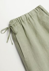 Jasnozielone lniane spodnie z elastyczną talią, sznurkiem do regulacji i bocznymi kieszeniami, charakteryzujące się gładką, przewiewną strukturą.