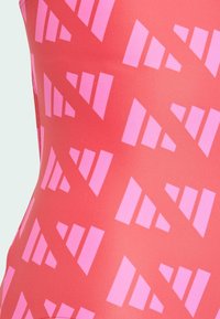One-piece swimsuit in coral with pink geometric pattern featuring triangular shapes. Smooth texture with a snug fit, suitable for water activities.
