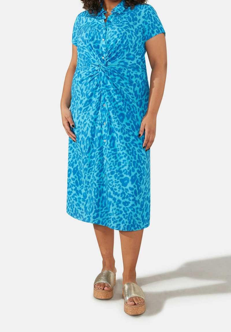 Kortärmad, knapp-up klänning i ljusblått med leopardmönster, som har en knutdetalj i midjan och en flödande kjol.