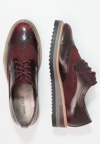 Derbies en cuir et daim bordeaux avec détails perforés, bout rond et semelle texturée contrastante. Lacets sur une chaussure, intérieur lisse.