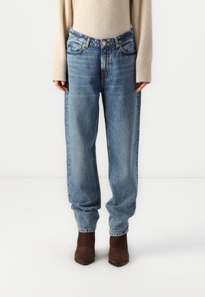 Light blue high-waisted jeans with a relaxed fit, featuring faded texture and five pockets, paired with brown ankle boots.