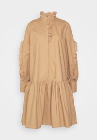 Robe en coton beige avec un col montant à volants, des manches longues et une jupe plissée. Présente des accents à volants le long des épaules et des poignets.