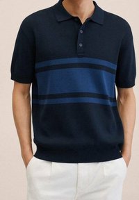 Camisa polo de color azul marino con manga corta, textura acanalada y rayas horizontales azules. Presenta un cuello clásico y una tapeta con tres botones.