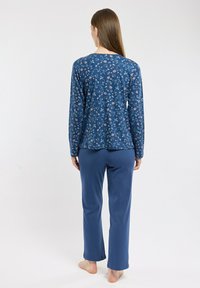 Ensemble de pyjama pour femme en bleu comprenant un haut à manches longues avec des motifs floraux et un pantalon bleu uni, fabriqué dans un tissu doux et confortable.