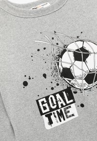 Grå stof med en sort-hvid fodbold, der rammer et net, ledsaget af teksten "MÅL TID" i fed, slidt skrifttype.