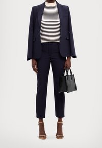 Navy blazer, striped white and navy top, tailored trousers, black handbag, and tan strappy heels. Smooth fabric, tailored fit, modern design.