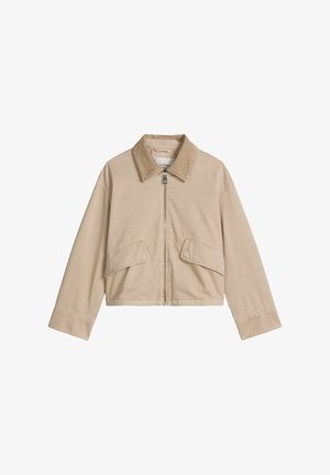 Beige cropped jack met een ritssluiting aan de voorkant, puntige kraag, lange mouwen en twee schuine klepzakken op een witte achtergrond.
