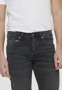 Zwarte spijkerbroek met een slim fit, voorzien van een tonale knoopsluiting, een vijf-pocket ontwerp en subtiele vervaging in de stoftextuur.