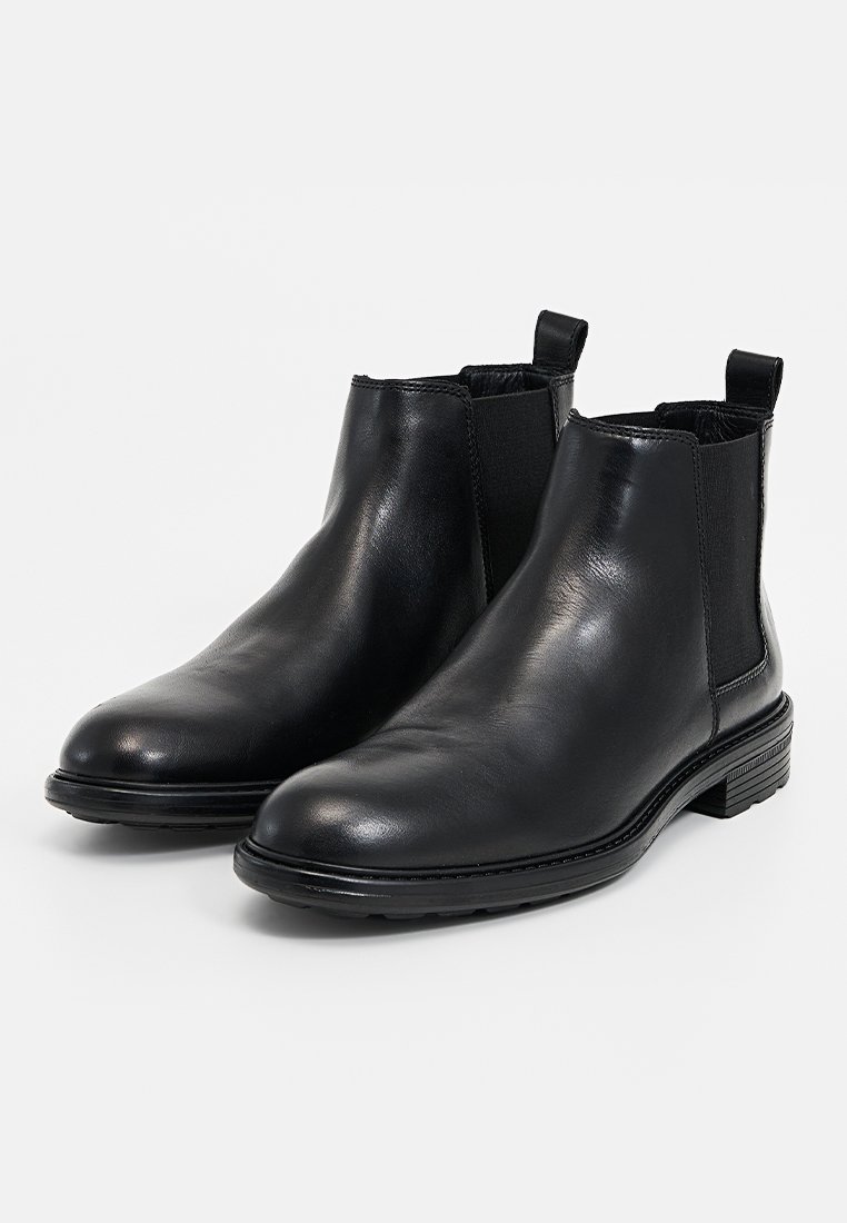Botas Chelsea de cuero negro con paneles elásticos en los lados, punta redonda y suela de goma texturizada. Incluyen tiradores para facilitar su uso.