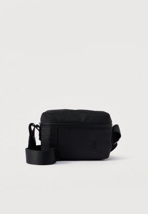 Kompletní černá crossbody taška se zipovým uzávěrem, nastavitelným popruhem a embosovaným logem "HUGO" na přední straně na jednobarevném pozadí.