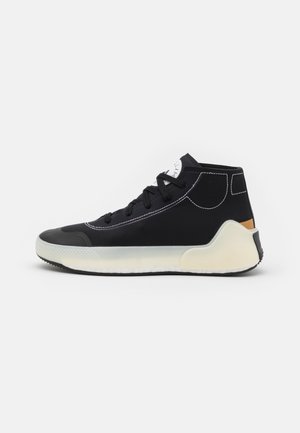 Sort højtop sneaker med hvid sål, sorte snørebånd, hvide syninger og en brun detalje på hælen, vist på en hvid baggrund.