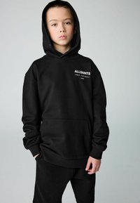 Sudadera negra de tejido suave y texturizado que cuenta con un bolsillo canguro, puños acanalados y un logo bordado en el pecho.