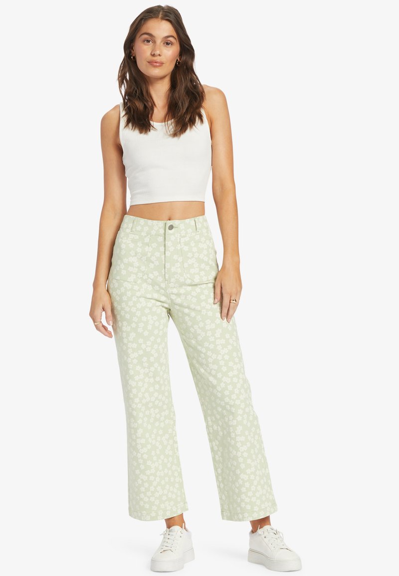 Pantalons larges à motifs de couleur vert clair avec un design floral, taille haute, et un débardeur blanc court. Caractérisés par un tissu lisse et une coupe décontractée.