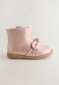 Cizme metalice roz până la gleznă, decorate cu o fundă, cu căptușeală moale și o talpă din cauciuc rezistentă pentru aderență. Textură netedă cu finisaj strălucitor.