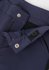 Laivansiniset housut, joissa on vetoketjullinen tasku, napilla kiinnitys ja joustava vyötärö. Ominaisuuksiin kuuluu sileä pinta ja metallipainikeyksityiskohta.