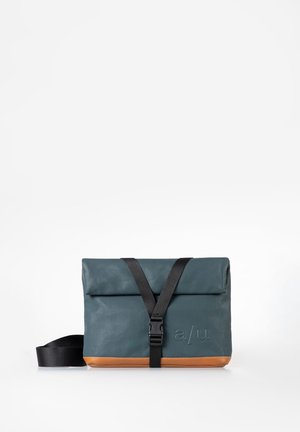 Borsa a tracolla compatta in pelle verde acqua e color sabbia con tracolla regolabile nera e chiusura frontale con fibbia, con logo "a/u" impresso sulla parte anteriore.